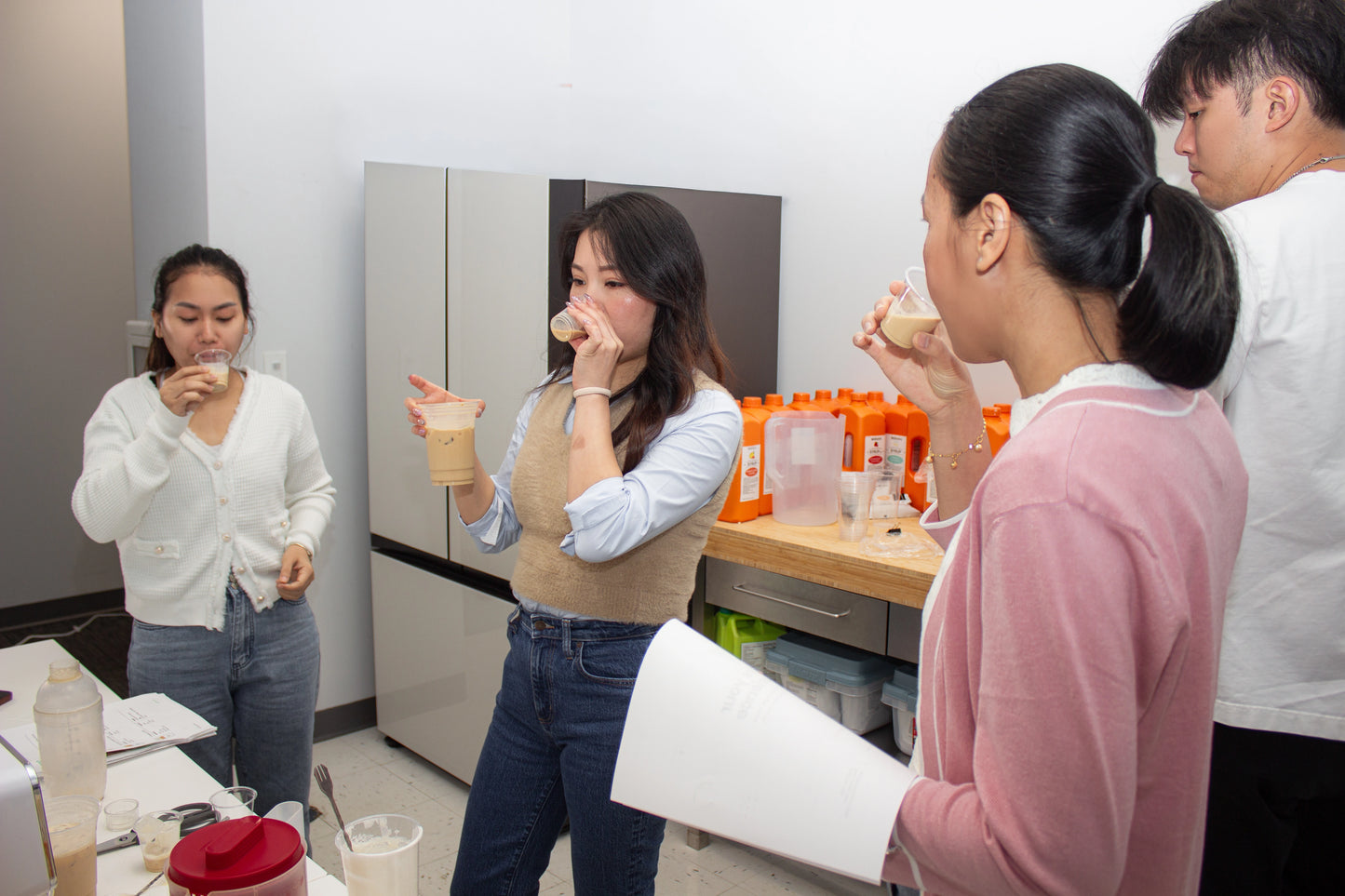 Group of people in a bubble tea kitchen setting, with one person holding a training guide.