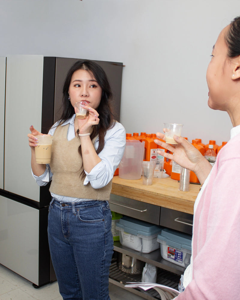 Three women in a kitchen setting, with one holding a Bubble Tea.